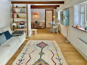 Ein gemütliches Wohnzimmer mit einer Couch, einem Couchtisch, einem Teppich und einem Bücherregal.
