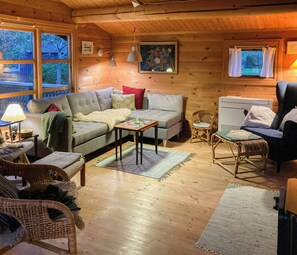 A cozy cabin interior with a sofa, armchairs, a table, and a fireplace. - Log house near Kisserup with vintage charm (Holbæk)