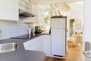 A modern kitchen with white cabinets, a stainless steel sink, and a built-in oven. - An intimate get-away by the Sandvig bay (Haderslev)