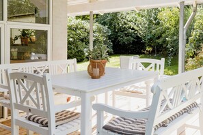 A white outdoor seating area with a table and chairs, surrounded by greenery. - An intimate get-away by the Sandvig bay (Haderslev)