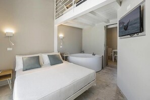 A modern hotel room with a large bed, a bathtub, and a balcony. - Luxury villa with pool in Aso Valley (Monterubbiano)