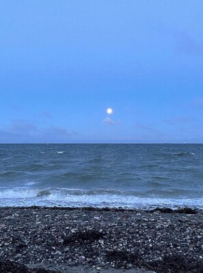 Une plage avec un rivage rocheux et une mer calme sous un ciel dégagé.