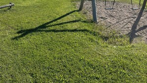 Ein Spielplatz mit Rutsche und Schaukeln vor blauem Himmel.