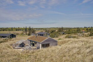 A modern house with a sloped roof, a patio with outdoor furniture, and a view of the surrounding landscape.