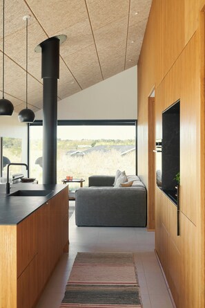 A modern kitchen with a large island, a built-in stove, and a large window offering a view of the outdoors.