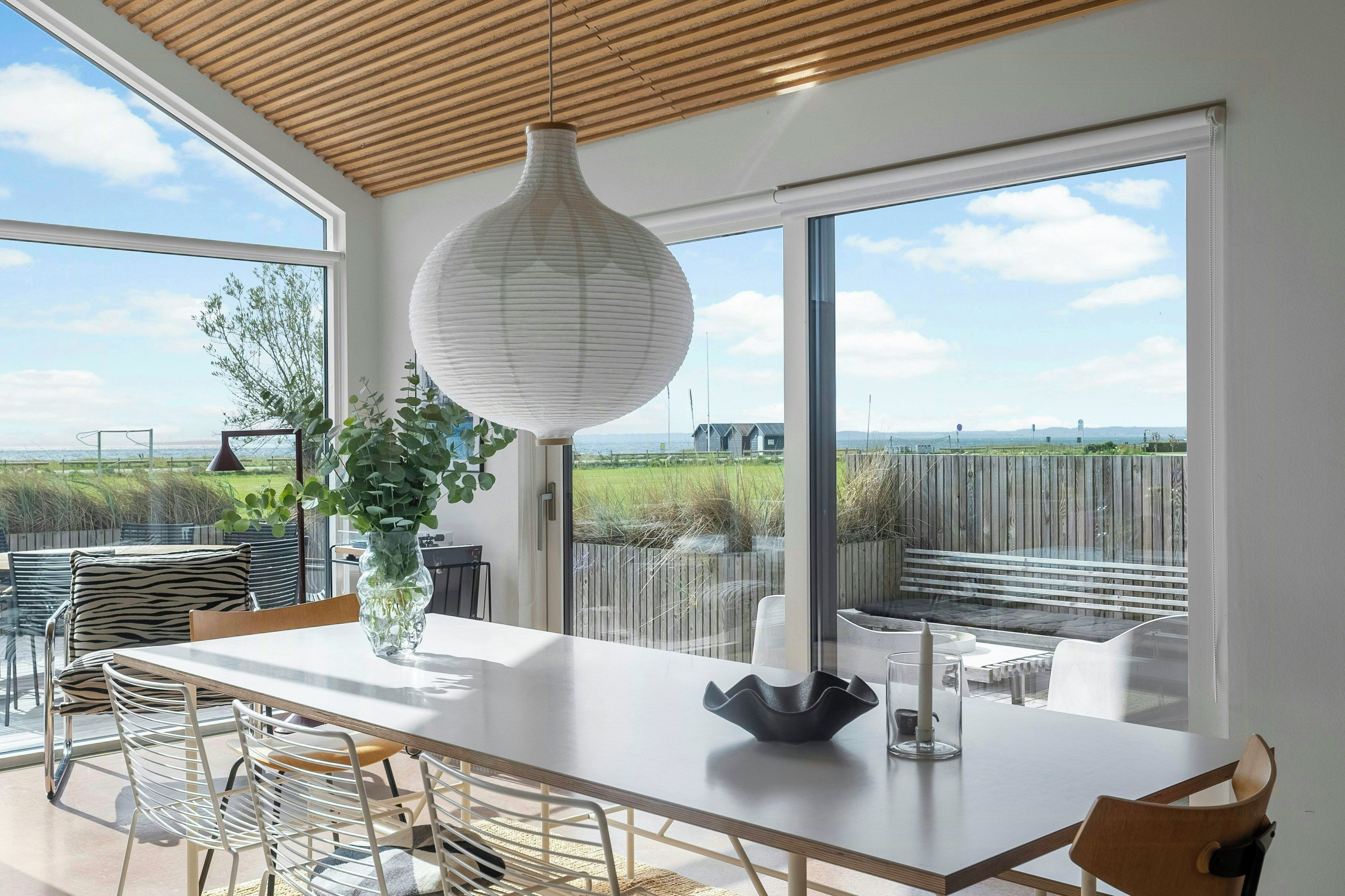 A modern dining area with a large table, chairs, and a hanging light fixture.