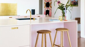 A modern kitchen with a central island, stools, and a hanging pendant light. - Newly built summer house with sea view (Haderslev)