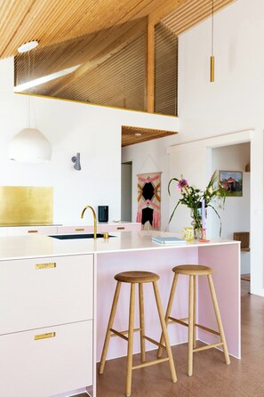 A modern kitchen with a central island, stools, and a hanging pendant light. - Newly built summer house with sea view (Haderslev)