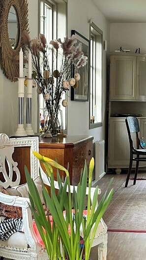 Ein Zimmer mit einem Holzschrank, einem Spiegel, einem Stuhl und einer Vase mit Blumen.