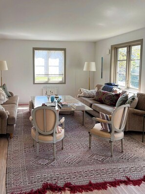 Ein Wohnzimmer mit einer Couch, Sesseln, einem Couchtisch und einem gemusterten Teppich.