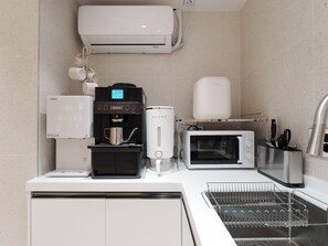 Une cuisine moderne équipée d’une machine à café, d’un four à micro-ondes, d’un grille-pain et d’un distributeur d’eau.