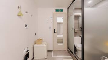 Un baño de hotel con inodoro, lavamanos, espejo, toallero y un pequeño armario.