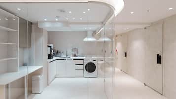 Una cocina moderna con lavadora, cafetera y un panel de vidrio.