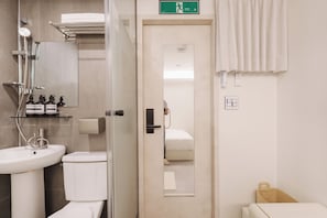 Un baño con lavamanos, inodoro, ducha y espejo.