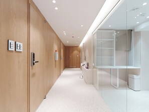 Un pasillo moderno de hotel con paredes de madera, una mampara de vidrio y un mostrador de recepción.