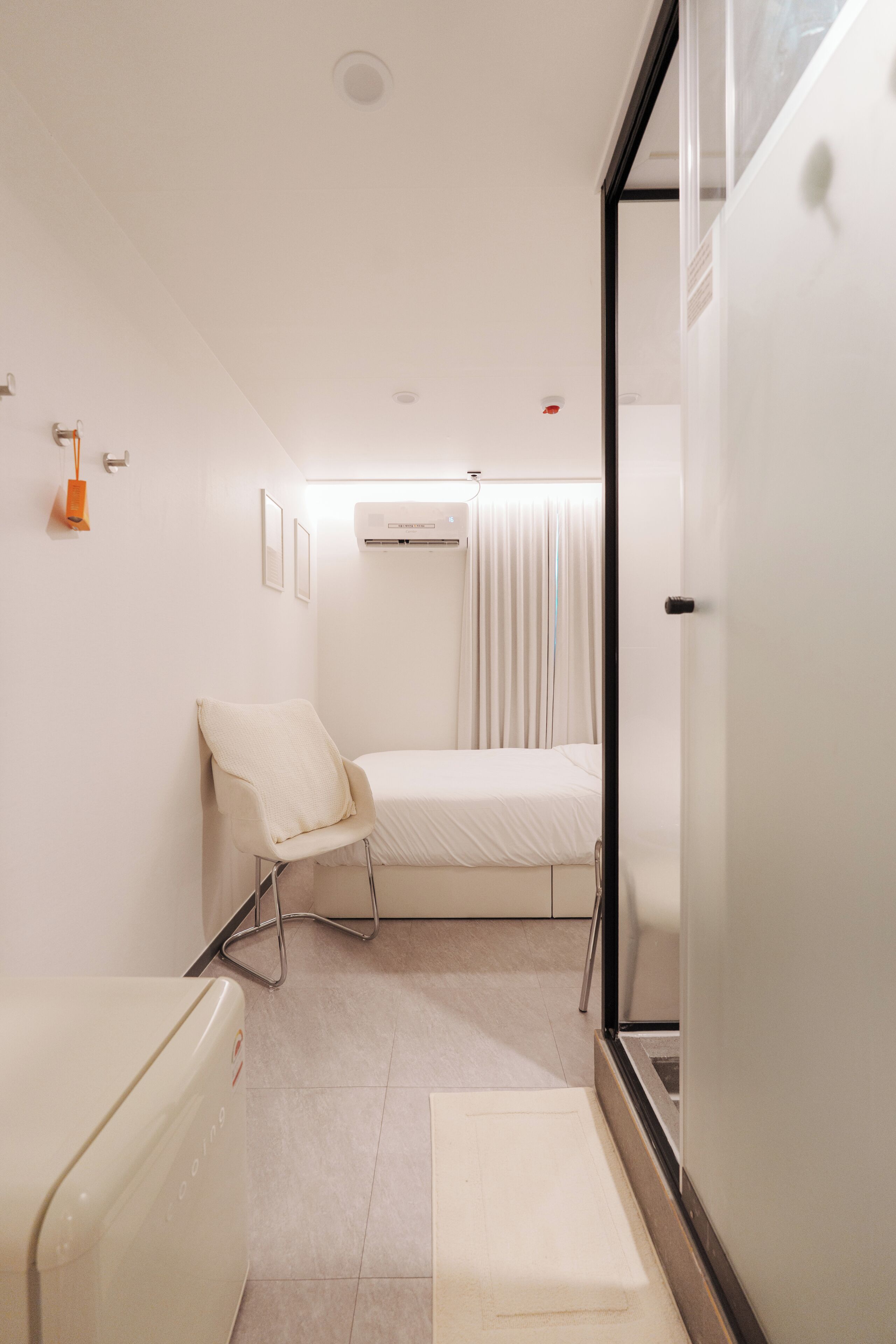 Una habitación de hotel moderna con una cama, una silla, una mesita y una ventana con cortinas.