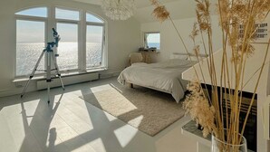 A bedroom with a large window, a bed, a tripod, and a view of the sea. - Modern villa with sea views in picturesque Mölle (Mölle)