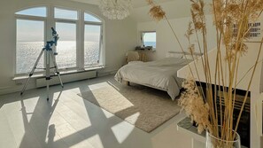 A bedroom with a large window, a bed, a tripod, and a view of the sea. - Modern villa with sea views in picturesque Mölle (Mölle)