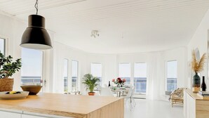 A modern kitchen with a wooden countertop, white cabinetry, and a hanging black pendant light. - Modern villa with sea views in picturesque Mölle (Mölle)