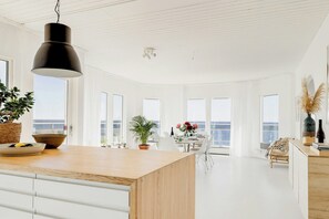 A modern kitchen with a wooden countertop, white cabinetry, and a hanging black pendant light. - Modern villa with sea views in picturesque Mölle (Mölle)