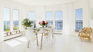 A spacious dining area with a view of the sea, white furniture, and potted plants. - Modern villa with sea views in picturesque Mölle (Mölle)