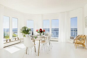 A spacious dining area with a view of the sea, white furniture, and potted plants. - Modern villa with sea views in picturesque Mölle (Mölle)