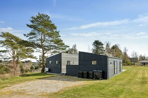 Un bâtiment moderne avec une allée en gravier et une pelouse verdoyante.