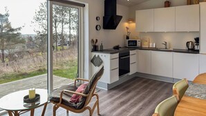 Eine moderne Küche mit großem Fenster, ein Essbereich mit Glastisch und eine gemütliche Sitzecke.