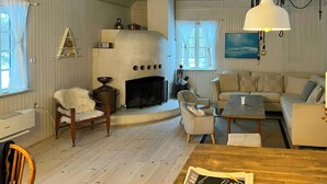 Een gezellige woonkamer met een open haard, een bank, een eettafel en een houten vloer.