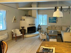 Ein gemütliches Wohnzimmer mit Kamin, einer Couch, einem Esstisch und Holzboden.