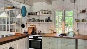 Een keuken met witte kastjes, een fornuis en verschillende keukengerei.