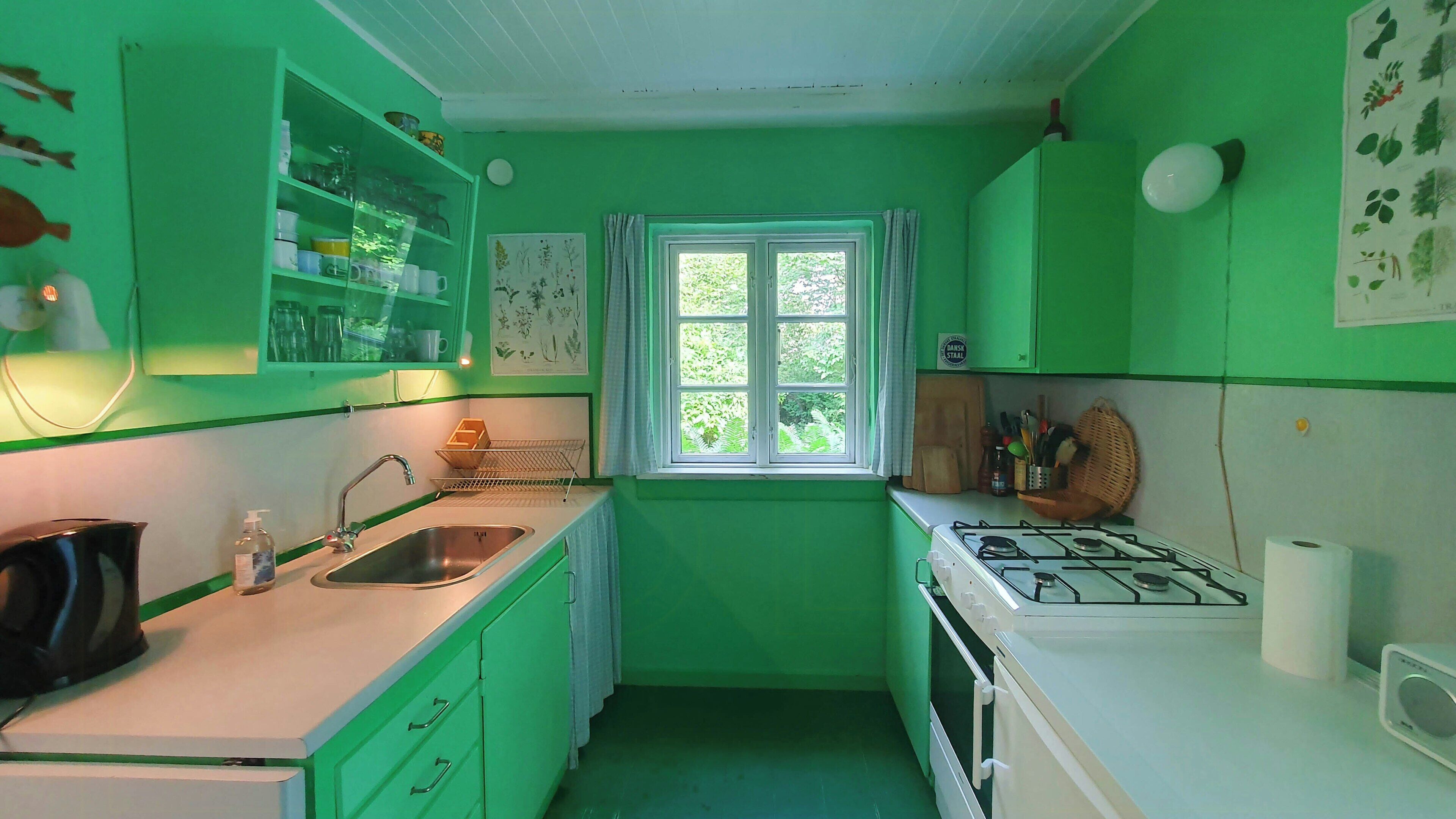 Una pequeña cocina con ventana, un fregadero y una estufa.