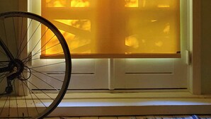 Una habitación con puerta de vidrio corredera, una bicicleta en primer plano y un tapete estampado en el suelo.