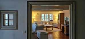 A living room with a sofa, a coffee table, and a television. - Thatched house on a Warft near Schlüttsiel (Dagebüll)