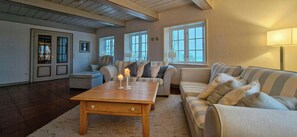 Ein Wohnzimmer mit Couchtisch aus Holz, gestreiften Sofas und einer Lampe.