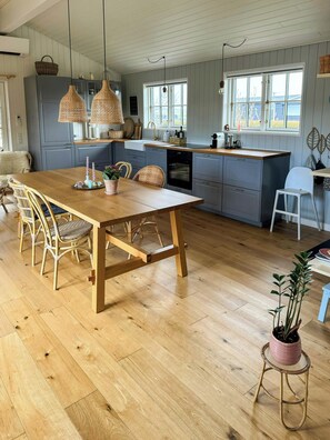 A kitchen with a wooden table, wicker chairs, a potted plant, and a window with a view. - Summer house by Nordstranden in Kerteminde (Kerteminde)