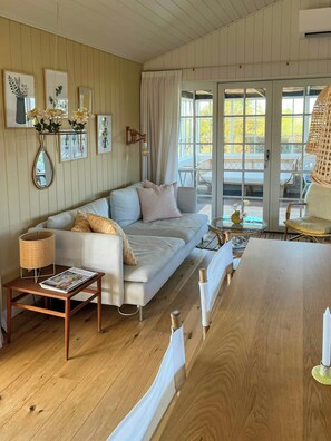 A cozy living room with a sofa, a wooden coffee table, and a dining table. - Summer house by Nordstranden in Kerteminde (Kerteminde)