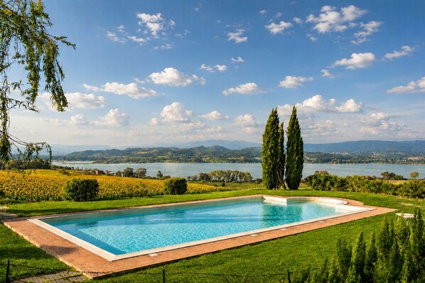 A rectangular swimming pool with a clear blue water surface, surrounded by a well-maintained lawn and a fence. - House with lakeview between Tuscany and Umbria (Castiglione del Lago)