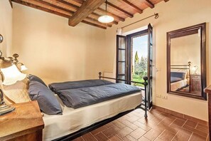 A bedroom with a bed, a nightstand, a lamp, a window with a view, and a wooden ceiling. - House with lakeview between Tuscany and Umbria (Castiglione del Lago)