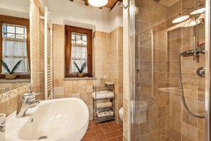 A bathroom with a bathtub, a shower, and a window with plants. - House with lakeview between Tuscany and Umbria (Castiglione del Lago)