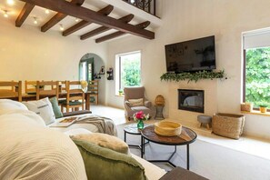 Ein Wohnzimmer mit einer Couch, Sesseln, einem Kamin und einem Fernseher.