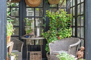 Ein Wintergarten mit Korbmöbeln, Topfpflanzen und einer Statue.