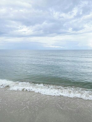 En strand med stilla vatten och en mulen himmel.