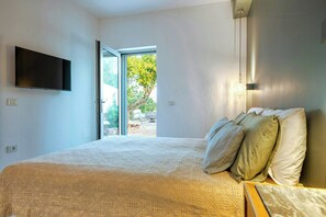 Ein Schlafzimmer mit Bett, Kissen, einem Fernseher und Blick ins Freie.