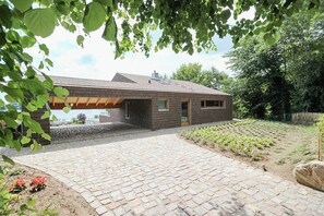 A modern house with a brick exterior, a paved driveway, and a garden area. - Riverside architect-designed garden apartment (Stapel)