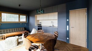 Een moderne keuken met een ingebouwde oven, een eettafel met stoelen en een bank.