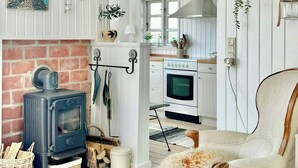Un interior acogedor con chimenea, estufa rústica, comedor y cocina con armarios de madera y estufa.