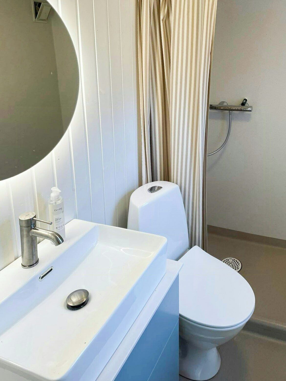 Une salle de bain avec un lavabo blanc, des toilettes, une douche et un miroir.