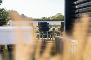 Una terraza con sillas y barandilla, con vista a un paisaje natural.