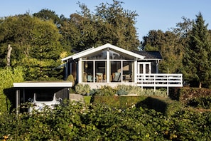 A modern house with a large glass window, a white porch, and a garage. - Holiday home with sunset views near Hvidbjerg (Børkop)